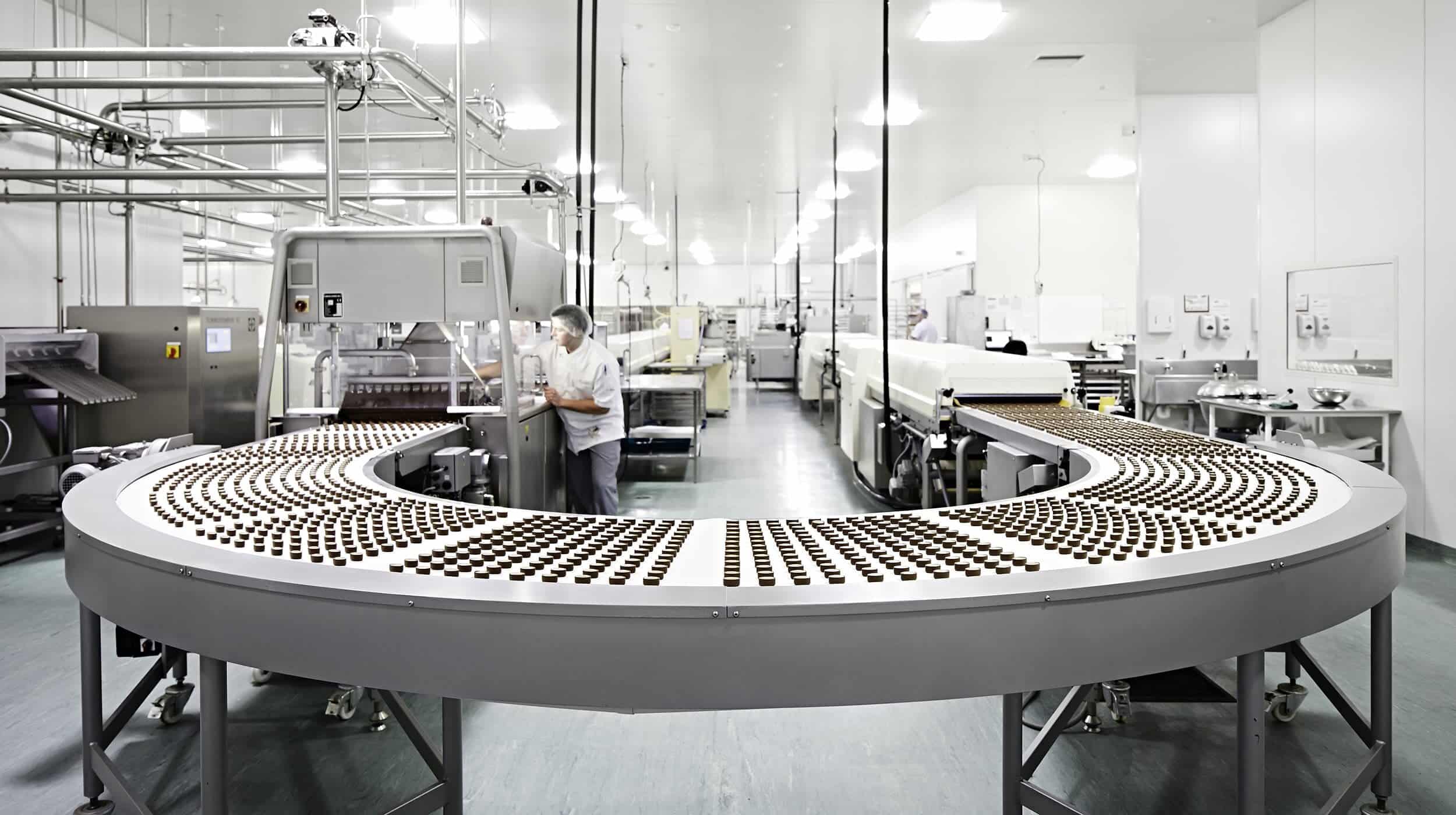 Modern chocolate production line with chocolate pieces on a conveyor belt in a clean factory, illustrating the process for hemp chocolate and traditional edibles comparison.